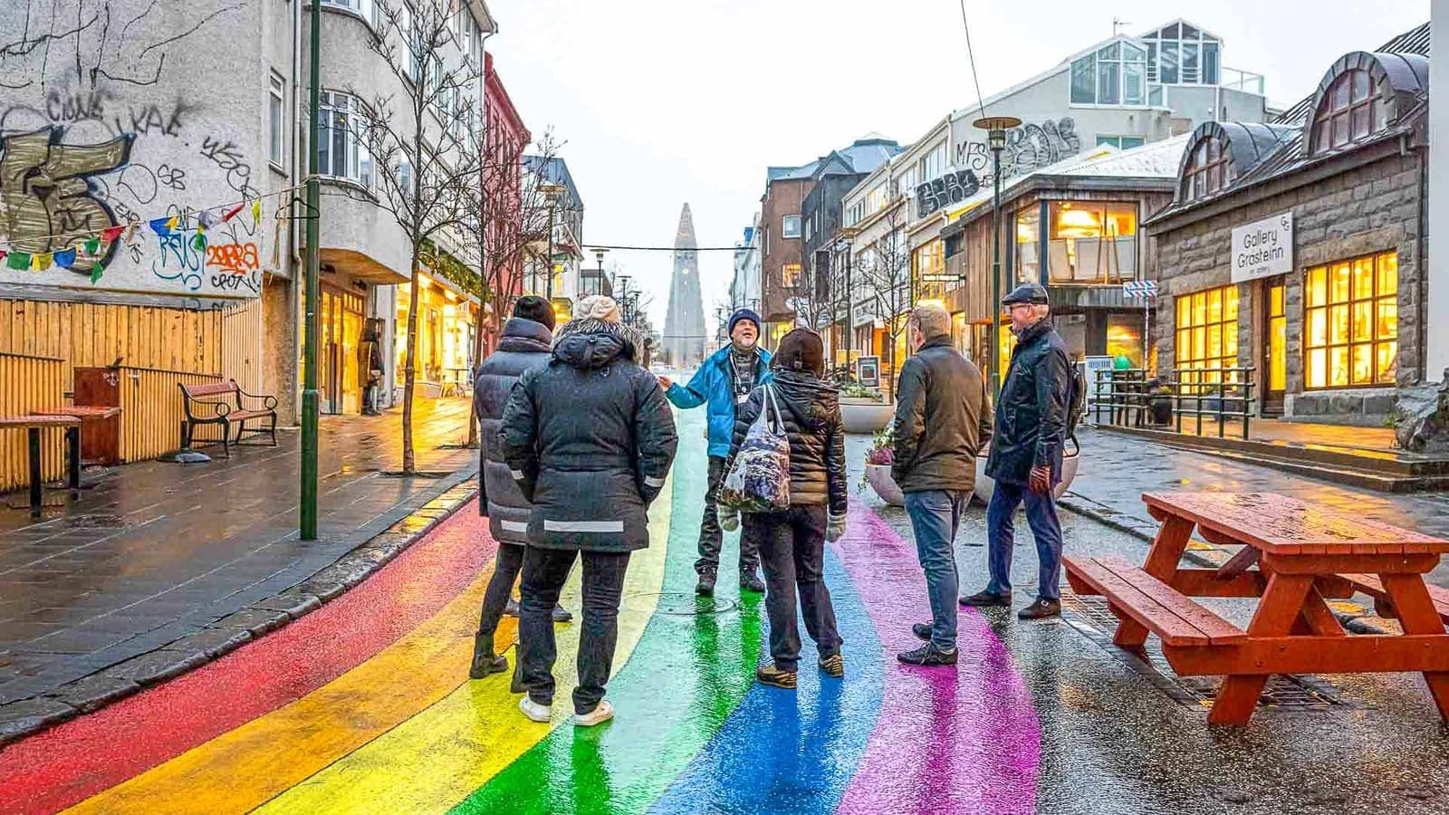 Travelers walking along Reykjavík rainbow street below Hallgrímskirkja